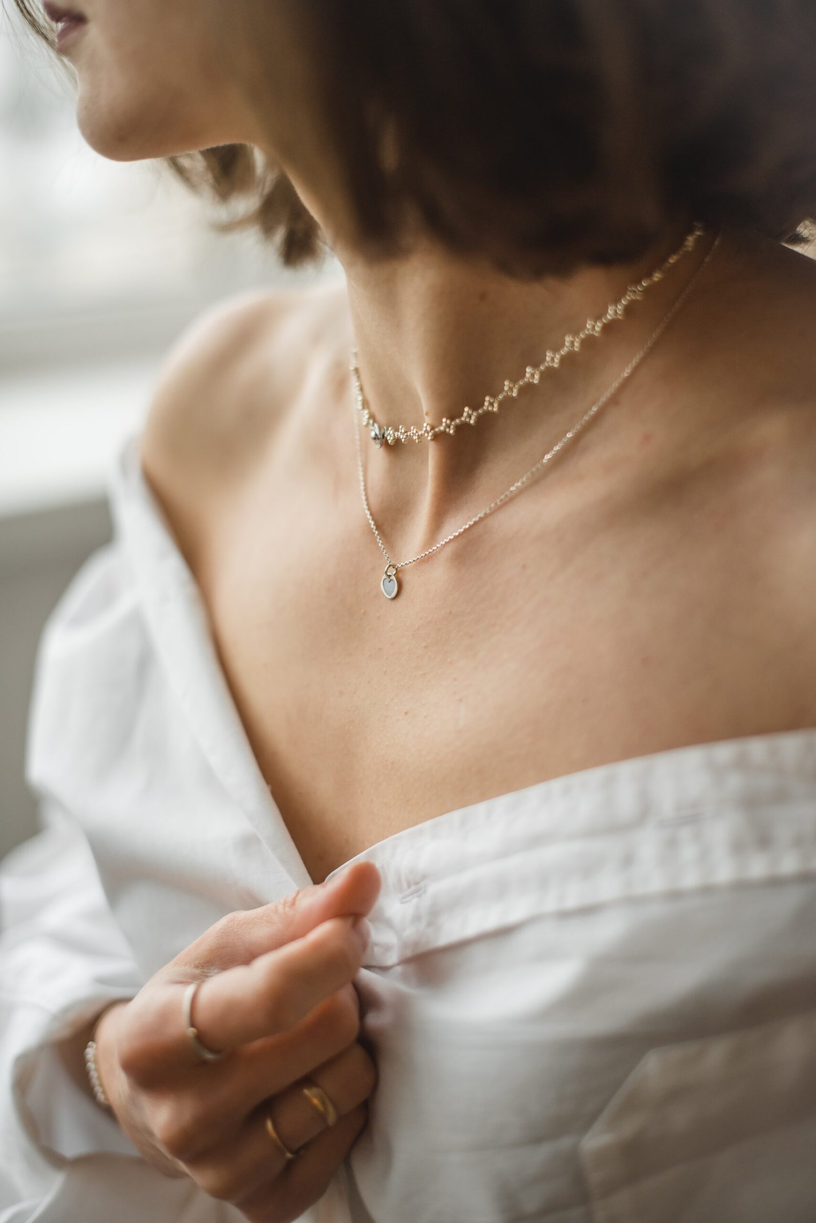 femme en chemise blanche à épaulettes portant un collier en argent
